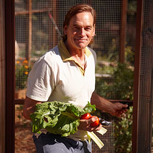 Darin Olien with freshly picked vegetables in a garden